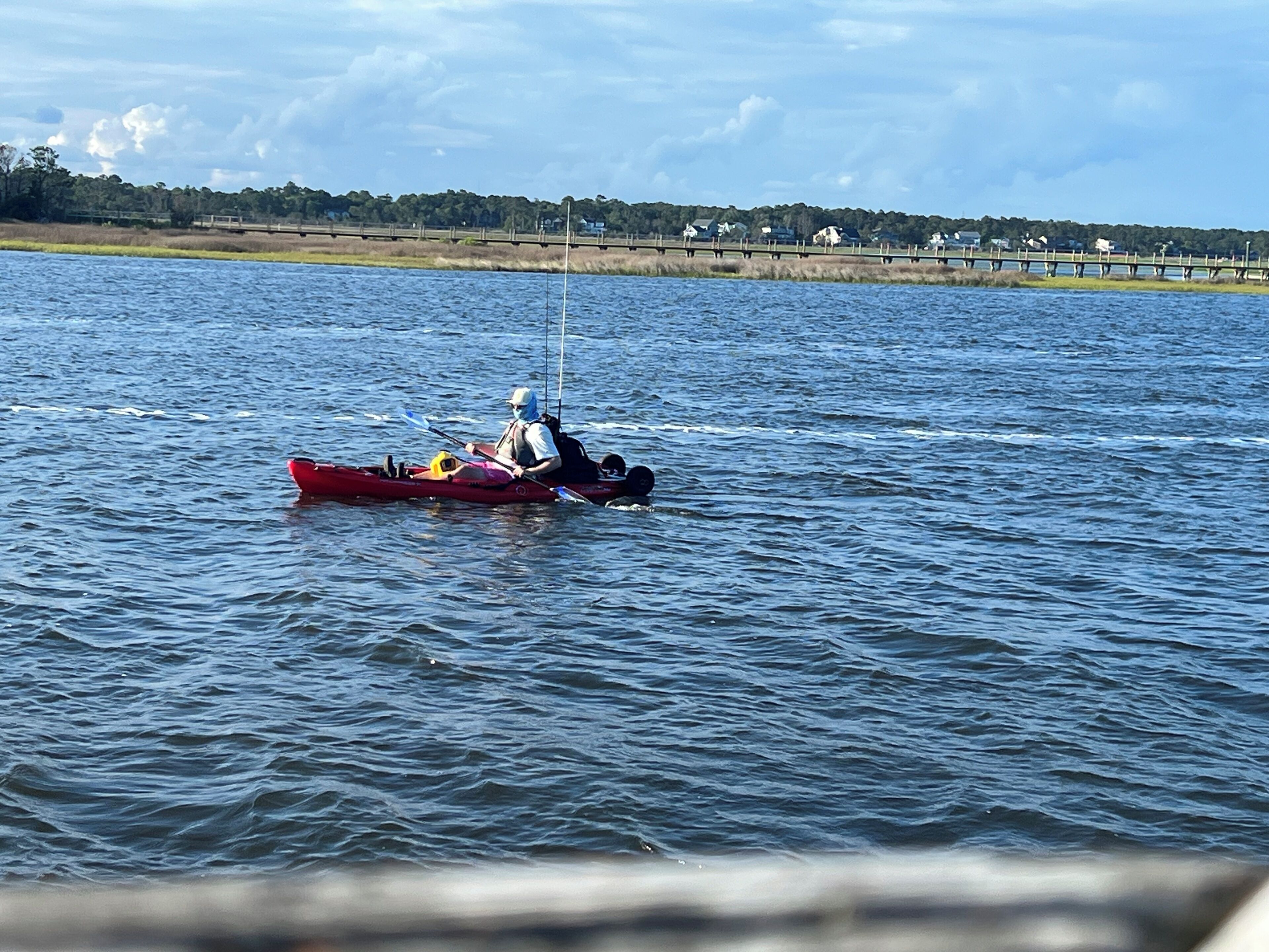 Une personne dans un kayak rouge, sur une étendue d'eau calme.
