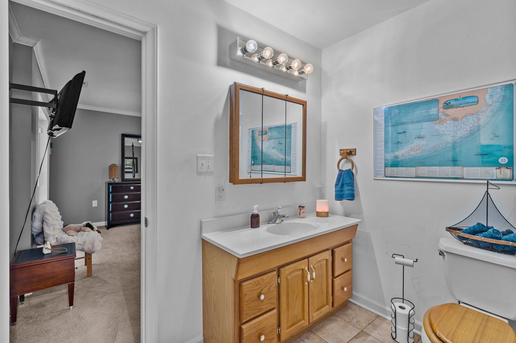 A bathroom with a wooden vanity, a large mirror, and a map on the wall.