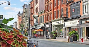 Rua com edifícios históricos, um café com mesas ao ar livre e uma lavanderia.