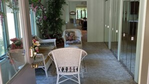 A narrow hallway with wicker chairs and a potted plant. - Nestled near woods and creek, this large home is near state parks and colleges.. (Hillsboro)