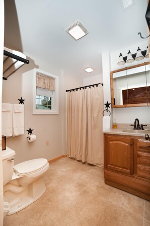 A bathroom with a toilet, sink, and shower curtain.