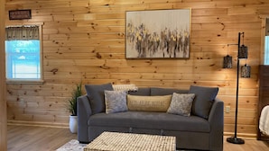 A cozy living room with a grey sofa, a wooden coffee table, and a painting on the wall. - Luxury cabin with mountain views (Flintstone)