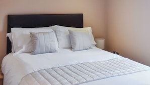 A neatly made bed with a quilted cover, a dark headboard, and two pillows. - 1 bedroom accommodation in Addlethorpe, near Skegness (Addlethorpe, near Skegness)