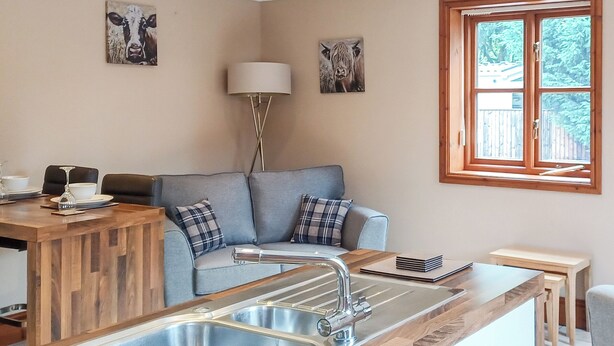 A kitchen with a wooden countertop, a sink, a dining area with a table and chairs, and a window with a view of greenery. - 1 bedroom accommodation in Addlethorpe, near Skegness (Addlethorpe, near Skegness)