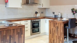 A modern kitchen with wooden countertops, stainless steel appliances, and a built-in island with bar seating. - 1 bedroom accommodation in Addlethorpe, near Skegness (Addlethorpe, near Skegness)