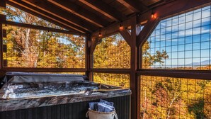 Un bain à remous dans un chalet en bois, avec vue sur les arbres aux couleurs automnales.