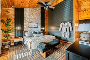 A bedroom with a bed, bedside table, bench, wall-mounted robe rack, and a ceiling fan.