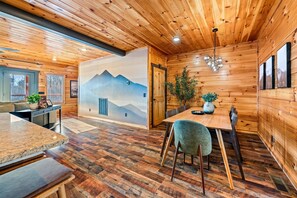 A wooden interior with a dining area, a mural, and a plant.
