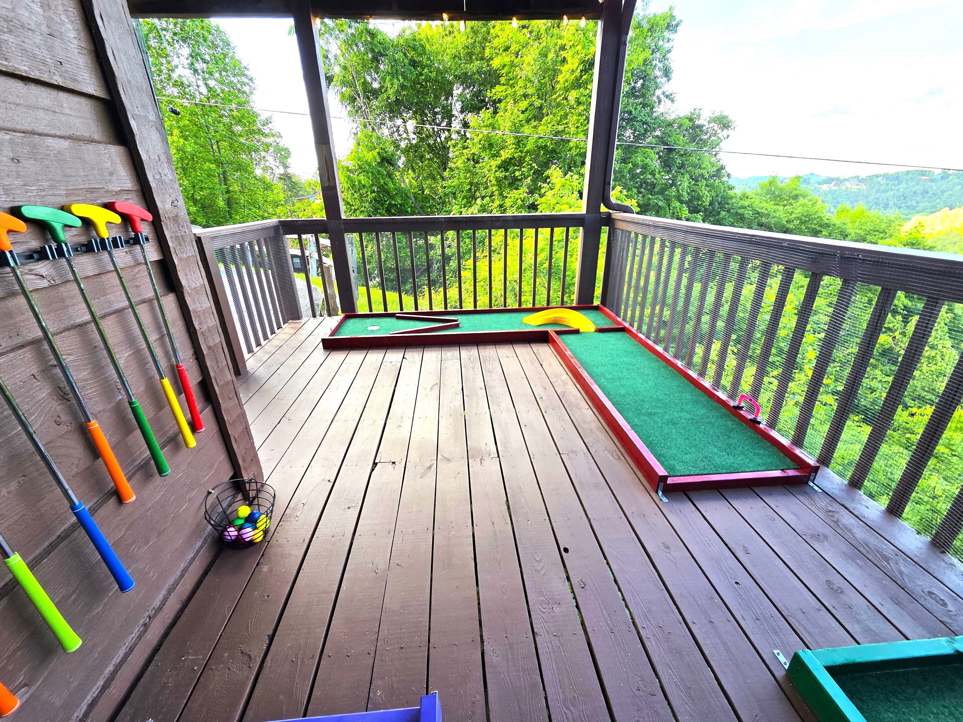 A wooden deck with a mini-golf setup and colorful golf clubs hanging on the wall.