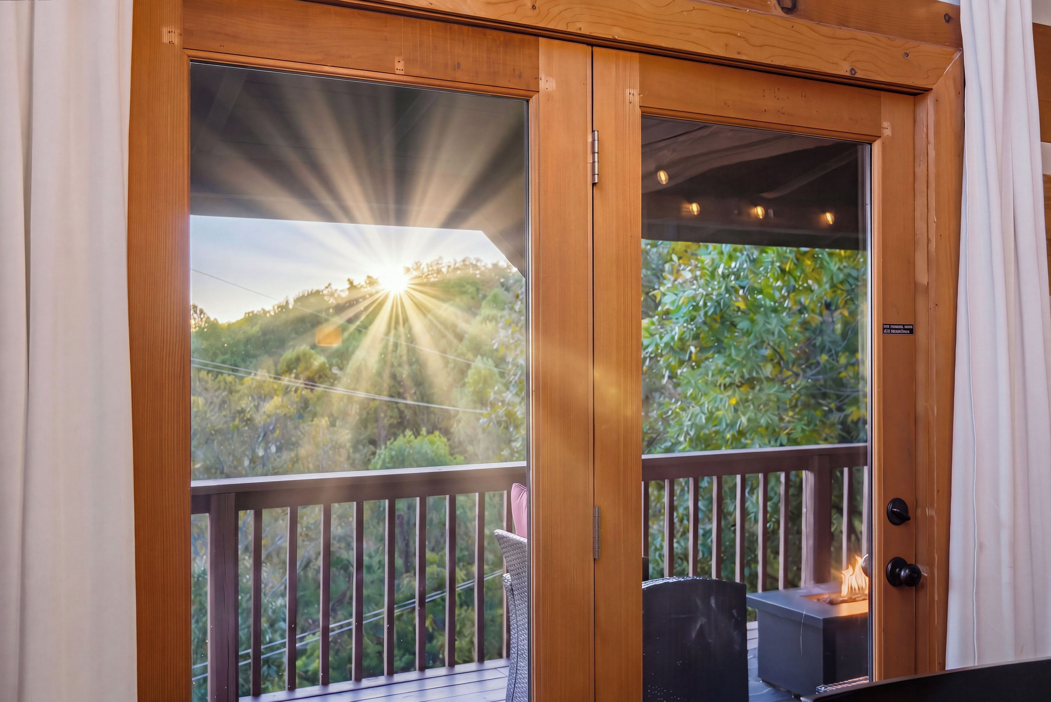 Una puerta de madera con vista a un paisaje iluminado por el sol a través de un panel de vidrio.