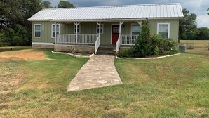 A single-story building with a porch, a red door, and a stone pathway leading to the entrance.