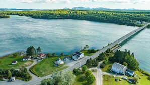 An aerial view of a coastal area with a bridge, houses, and a road.