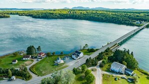An aerial view of a coastal area with a bridge, houses, and a road.