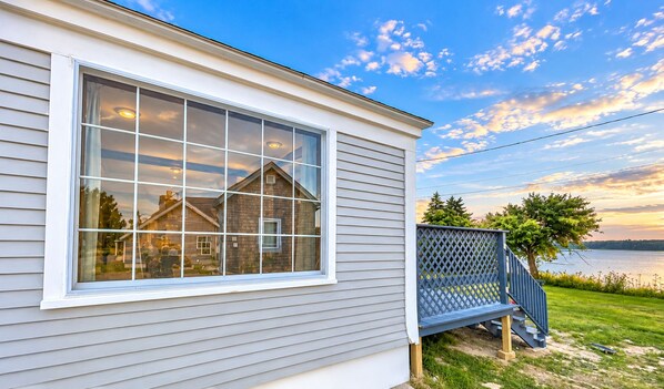 A house with a large window, a deck, and a view of a lake.
