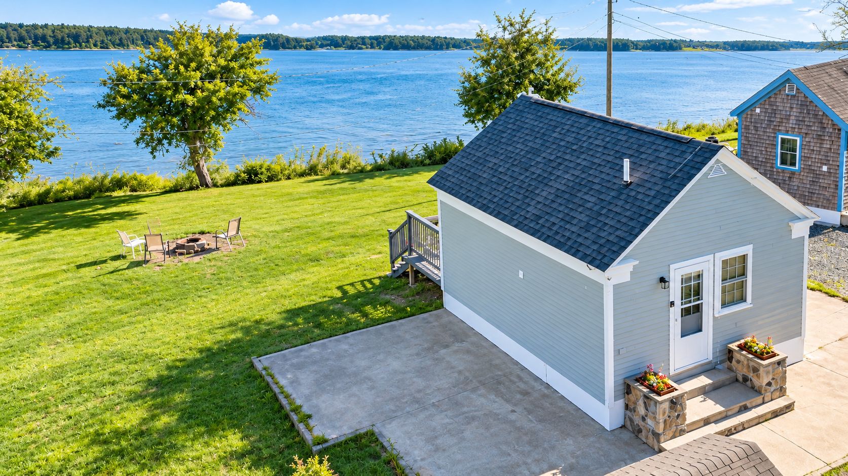 Une propriété résidentielle comprenant une petite maison, une cour gazonnée et une vue sur un lac.