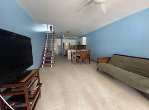 A living room with a TV, sofa, and a staircase leading to a kitchen.