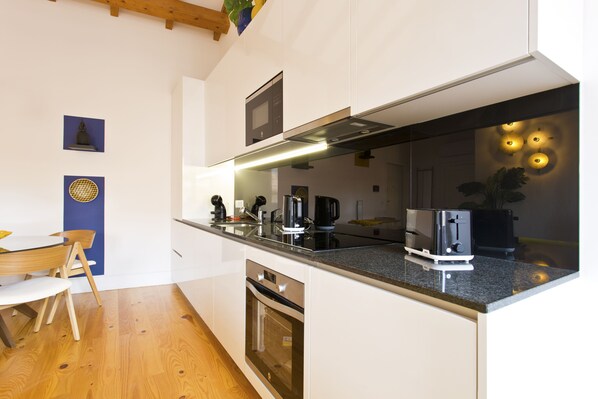A modern kitchen with white cabinetry, a built-in oven, a stainless steel range hood, and a granite countertop.