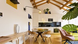 A modern kitchen with white cabinets, a dining table with chairs, and a large window. - Boutique Rentals- The Alma Apt w/balcony (Porto)