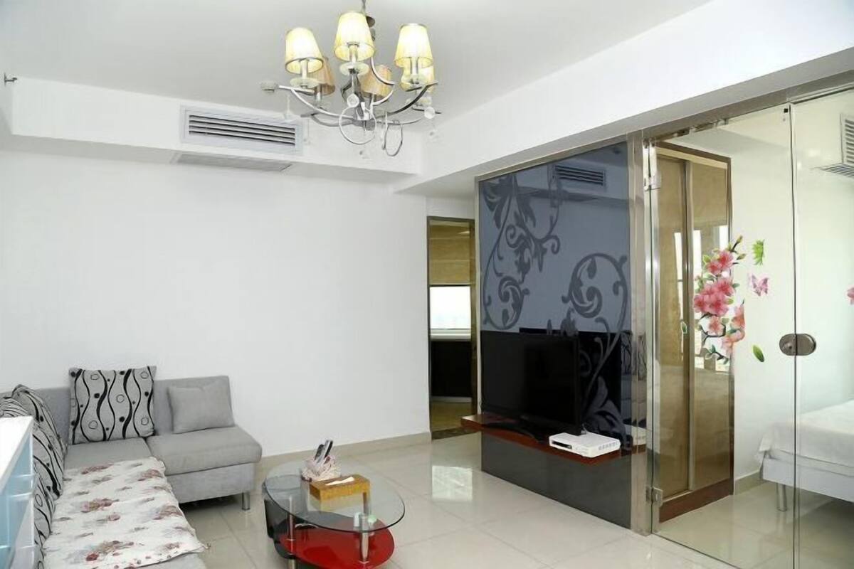 Una sala de estar moderna con un sofá, una mesa de centro de vidrio, un televisor y un divisor de ambiente de vidrio.