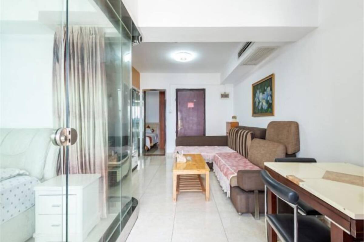Una sala de estar moderna con un separador de vidrio, un sofá, una mesa de madera y un comedor.