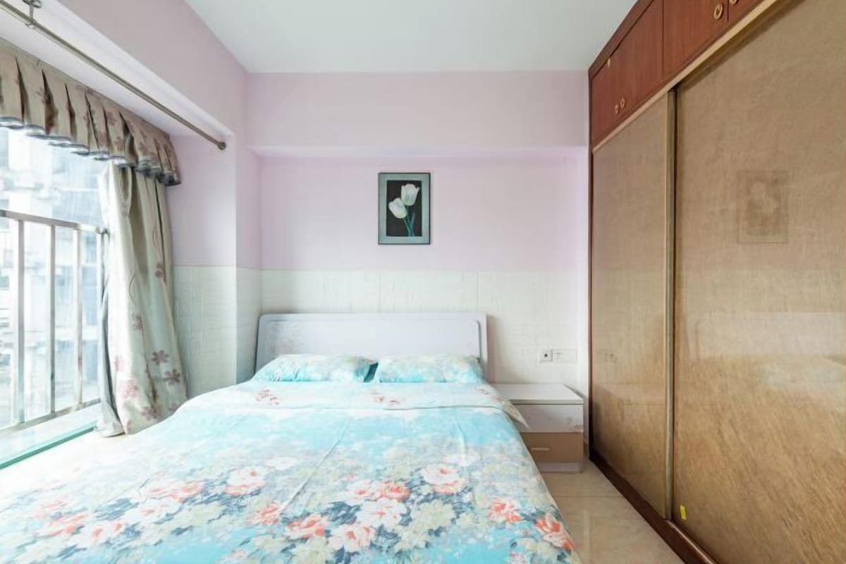 Quarto com cama, janela com cortinas, um quadro na parede e um guarda-roupa.