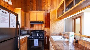 Una cocina compacta con armarios de madera, estufa, microondas y pileta.
