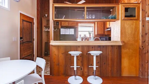 Una cocina con paredes de madera, una encimera blanca y dos taburetes.