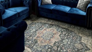 A living room with a blue sectional sofa, a small side table with a lamp, and a patterned rug. - Historic House in heart of Altenburg (Altenburg)
