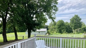 A covered outdoor area with a white deck, white chairs, and a view of a green field and trees. - Historic House in heart of Altenburg (Altenburg)