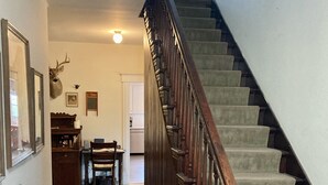 A staircase with wooden railings leading to a second floor. A dining table and chairs are positioned in the foreground, and a deer head mounted on the wall is visible. - Historic House in heart of Altenburg (Altenburg)