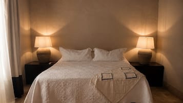Un lit recouvert d’une couvre-lit blanche et agrémenté de deux lampes de chevet posées sur des tables de nuit en bois.