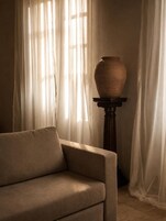 Quarto com sofá e vaso sobre um pedestal.