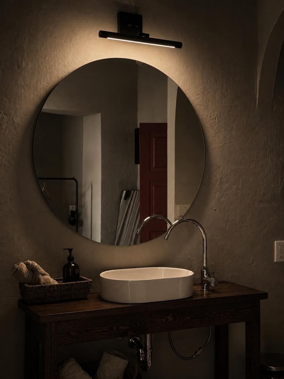 A bathroom with a round mirror, a white sink, and a towel rack.