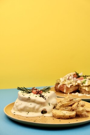 A dessert plate with a creamy white dessert, garnished with herbs and a sprig of rosemary, accompanied by a side of roasted potato slices. - Hotel Boutique Casa Damiana (Lagos de Moreno)