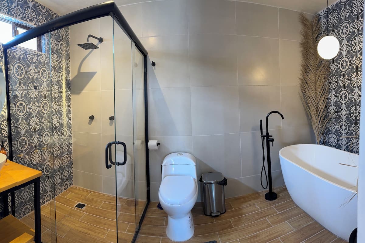 A modern bathroom with a glass-enclosed shower, a white sink, a toilet, and a bathtub.