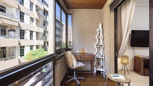 Un balcón con escritorio, silla y una mesita.