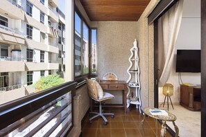 Un balcón con escritorio, silla y una mesita.