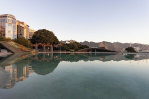 Un hotel con piscina que refleja los edificios y montañas circundantes.