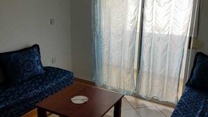 A room with two patterned sofas, a wooden coffee table, and a large window with sheer curtains. - Nice T3 with terrace - MIXTA residence (Martil)