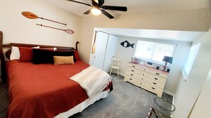Un dormitorio con cama, ventilador de techo, cómoda, silla y decoración de peces en la pared.