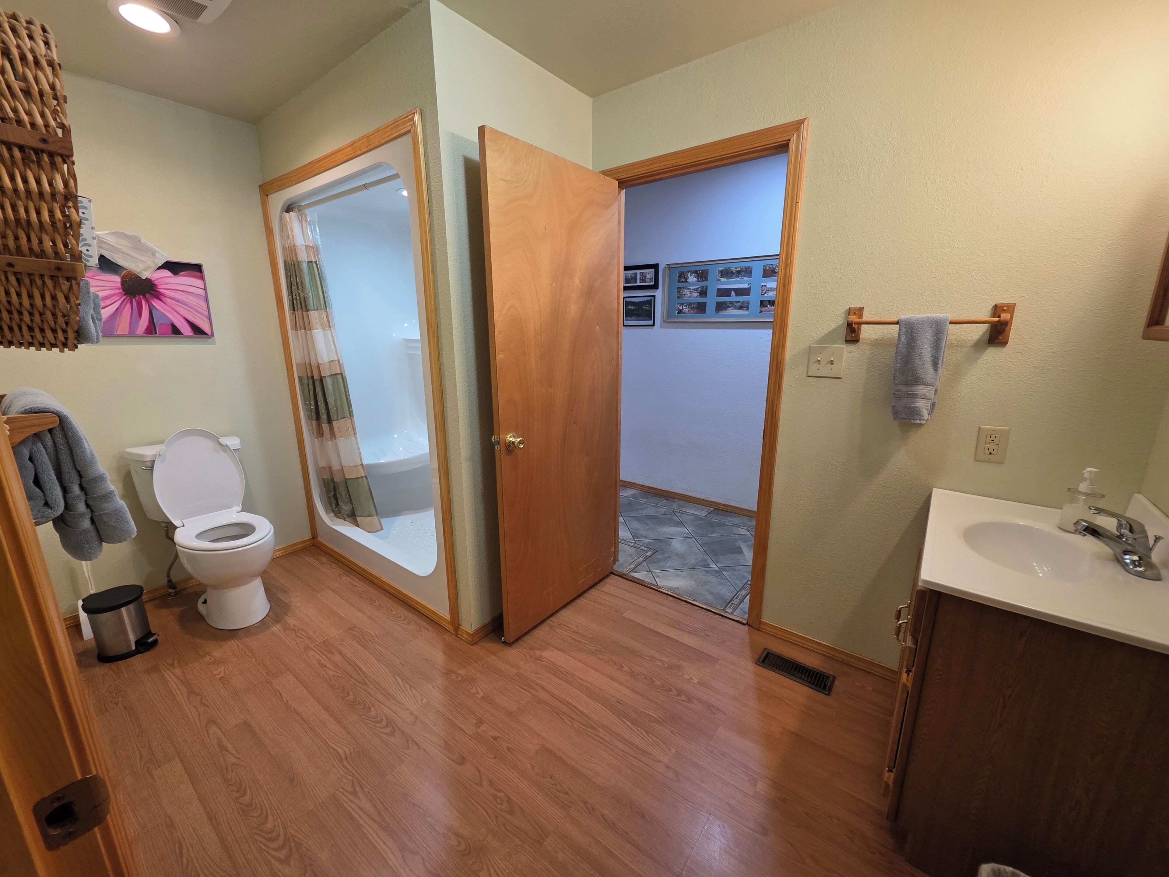 Un baño con inodoro, ducha, lavabo y suelo de madera.