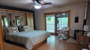 Ein Schlafzimmer mit einem Bett, Holzboden, Deckenventilator und großen Fenstern.