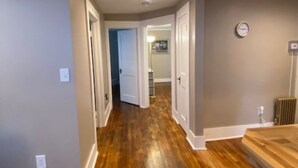 A hallway with wooden flooring, white doors, and a clock on the wall. - GORGEOUS NEW RENNOVATED APT! 1 month or more! Calling TRAVEL NURSES! (Gloversville)