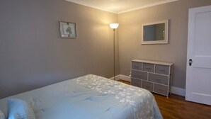 A bedroom with a bed, a dresser, a nightstand, and a wall-mounted mirror. - GORGEOUS NEW RENNOVATED APT! 1 month or more! Calling TRAVEL NURSES! (Gloversville)
