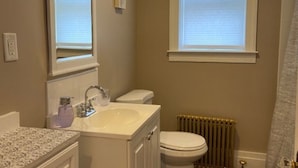 A bathroom with a sink, toilet, and radiator. - GORGEOUS NEW RENNOVATED APT! 1 month or more! Calling TRAVEL NURSES! (Gloversville)