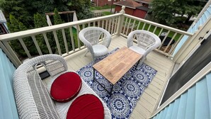 A balcony with wicker furniture, a wooden table, and a patterned rug. - Downtown Dream in Owensboro Ky (Owensboro)