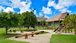 Ein Spielplatz mit Schaukeln, einer Rutsche und einer Kletteranlage.