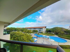 Blick auf ein Hotel mit Poolbereich, darunter mehrere Pools und Liegestühle.