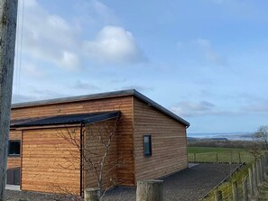 A wooden building with a sloped roof, a small window, and a door. - Galloway View -  a lodge that sleeps 4 guests  in 2 bedrooms (Gatehouse of Fleet)