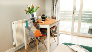A dining area with a table, chairs, a radiator, and a view through a glass door. - Beths Bothy -  a pod that sleeps 2 guests  in 1 bedroom (Gatehouse of Fleet)